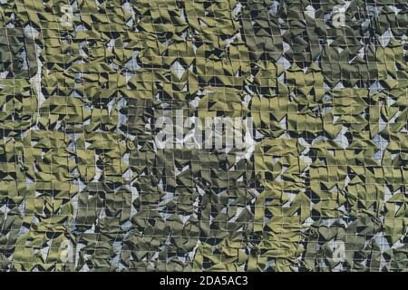 La texture de la maille de camouflage dans différentes nuances de couleur verte avec de minces carrés d'une corde de filet blanche à l'intérieur, sur un fond bleuâtre Banque D'Images