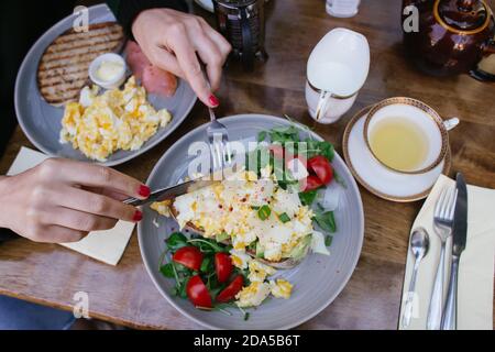 brunch ou petit déjeuner dans un restaurant : 2 assiettes avec sandwichs à l'avocat, œufs, salade, tomates, saumon et thé Banque D'Images