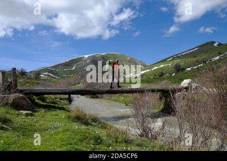 Randonneur avec sac à dos traversant un pont primitif de troncs en bois sur la crique dans le parc Nebrodi, en Sicile Banque D'Images