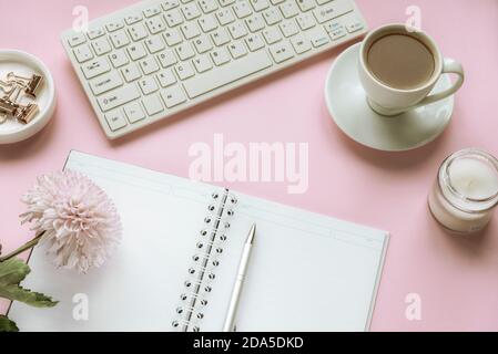 Espace de travail confortable pour femme avec fleurs de chrysanthème, bloc-notes vierge, tasse de café et bougie. Vue de dessus, plan d'appartement Banque D'Images