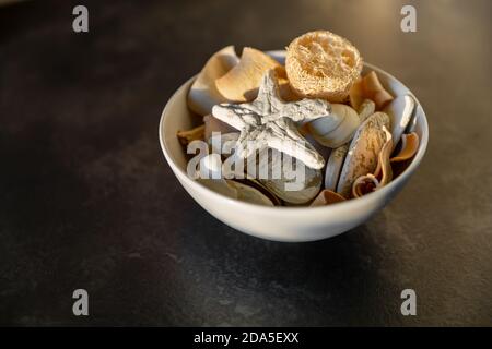 Bol de potpourri avec une étoile de mer, des rochers et des coquillages dans un bol sur fond noir Banque D'Images