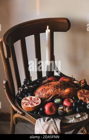 Canard rôti au four entier dans des fruits de saison mûrs pour les vacances de Thanksgiving ou la fête de la veille de Noël sur plateau sur tabouret en bois, vue du dessus. Repas de confort traditionnel pour les vacances d'automne ou d'hiver Banque D'Images