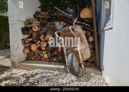 Wheel barrow dans le jardin par la pile de billes Banque D'Images