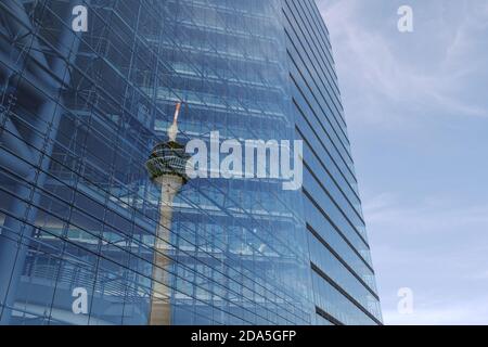 Extérieur et bas angle avec détail reflétant Rheinturm, tour du Rhin, sur la façade de bâtiment en verre de la tour Stadttor contre ciel bleu. Banque D'Images