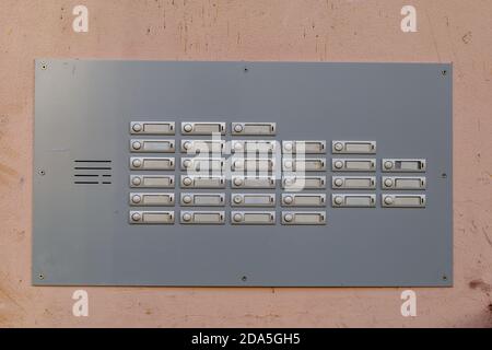 Sonnettes de porte en métal avec des étiquettes de nom vides sur le mur rose. Sonnette sans nom. Intercom extérieur à l'extérieur du bâtiment résidentiel. Banque D'Images