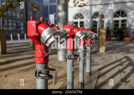 Concentration sélective au poteau incendie rouge sur le trottoir ou la place. Tuyau et pompe de poteaux incendie pour la lutte contre l'incendie et l'extinction. Banque D'Images