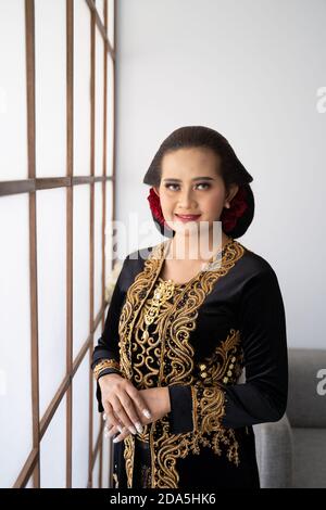 Portrait d'une femme traditionnelle javanaise en costume. Debout près de la fenêtre Banque D'Images