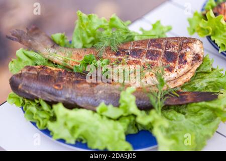 bar frit sur une assiette avec des légumes verts Banque D'Images