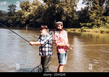 Deux pêcheurs se détendent ensemble tout en pêchant sur le lac le matin. Aventures de pêche à la mouche. Jour de la famille. Si vous le souhaitez, il y avait des poissons. Homme au bord de la rivière Banque D'Images