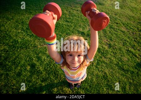 Activité enfant. Sport amusant. Enfant avec haltères. Grand angle. Banque D'Images