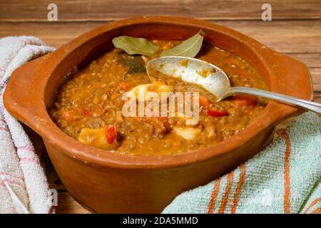 Pot en argile avec ragoût de lentilles maison, tomate, chorizo espagnol, viande et pommes de terre avec cuillère. Banque D'Images