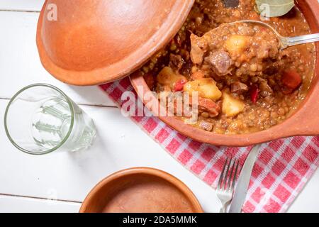 Pot en argile avec ragoût de lentilles maison, tomate, chorizo espagnol, viande et pommes de terre. Vue zénital. Banque D'Images