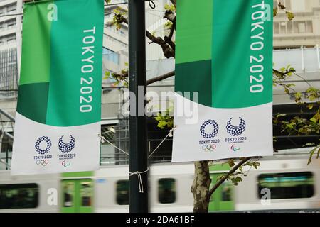 Tokyo Olympics 2020 bannières accrochées à un lampadaire dans la région de Shibuya à Tokyo. Un train passe en arrière-plan. Flou de mouvement. (Février 2020) Banque D'Images