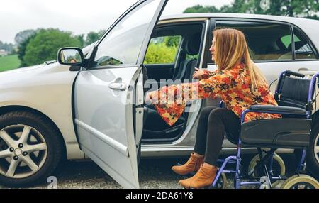 Woman in wheelchair obtenir on car Banque D'Images