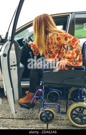 Woman in wheelchair obtenir on car Banque D'Images