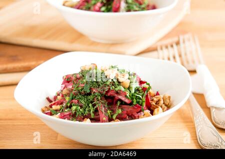 Salade délicieuse avec des betteraves et des noix bouillies. Belle portion du plat dans un bol blanc. Banque D'Images