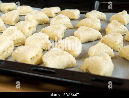 Les biscuits triangulaires au fromage cottage cru sont sur la plaque de cuisson. Vue latérale. Banque D'Images