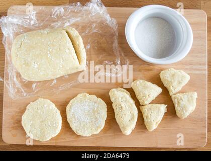 La pâte à biscuits caillé est coupée en moules. Saupoudrer de sucre. Banque D'Images