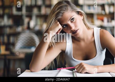 La jeune fille étudiante de l'université s'ennuie, frustrée et accablée par l'étude des devoirs Banque D'Images