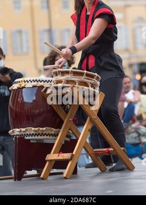 Fille jouant des tambours de la tradition musicale japonaise lors d'un événement public en plein air. Banque D'Images