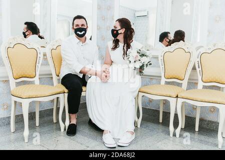 Mariage pendant l'épidémie du coronavirus. Mariée et marié dans des masques médicaux de protection. Les Marrieds et la pandémie Covid-19. Banque D'Images