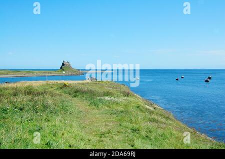 Vue sur le château de Lindisfarne, la baie du port et les bateaux Banque D'Images