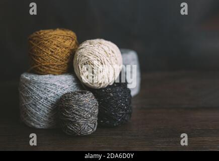 Skeins douillets en fil pour tricoter à la main sur un fond en bois sombre. Arrière-plan pour la maison artisanale et lente. Mise au point sélective. Banque D'Images