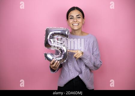 Belle femme portant un pull violet décontracté sur fond rose Belle femme portant un pull violet décontracté sur fond rose souriez Banque D'Images