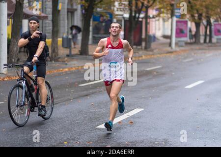 DNIPRO, UKRAINE - 16 SEPTEMBRE 2018: Jeune homme sur un vélo vidéo de tir de coureur pendant 21 km de distance de ATB Dnipro Marathon sur Dnipro pluvieux c Banque D'Images