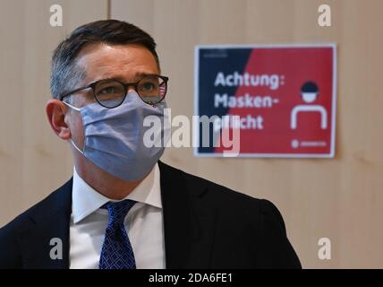 10 novembre 2020, Hessen, Wiesbaden: Boris Rhein (CDU), président du Parlement de l'État, se trouve dans le bâtiment du Parlement de l'État avec protection de la bouche et du nez devant un panneau avec l'inscription "attention: Masques obligatoires". En raison de la pandémie de corona, le conseil des aînés du Parlement de l'État avait ordonné le port d'un protecteur de la bouche et du nez pour se protéger contre l'infection par le virus. La faction de l'AfD de Hesse veut empêcher le port obligatoire de masques pour les députés dans leurs sièges aux sessions du Parlement de l'État de Wiesbaden. Photo: Arne Dedert/dpa Banque D'Images