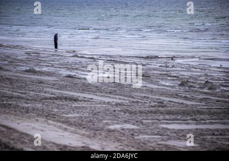 Lubmin, Allemagne. 05ème novembre 2020. Un homme est à la recherche de pierres sur la plage presque déserte, qui a été lavé à nouveau il y a quelques jours, à la mer Baltique. En tant que mesure de protection de la couronne, les touristes doivent quitter le Mecklembourg-Poméranie occidentale d'aujourd'hui au plus tard. Dans toute l'Allemagne, un verrouillage partiel de quatre semaines a commencé le 02.11.2020 pour ralentir la propagation du virus corona. Credit: Jens Büttner/dpa-Zentralbild/ZB/dpa/Alay Live News Banque D'Images