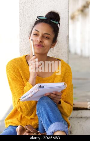 Portrait de la jeune femme africaine assise à l'extérieur de la pensée et de l'écriture dans le livre Banque D'Images