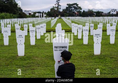 Bandung, Indonésie. 10 novembre 2020. Un garçon met une fleur sur une pierre tombale lors de la commémoration de la Journée nationale des héros au cimetière des héros de Cikutra à Bandung, West Java, Indonésie, le 10 novembre 2020. La Journée nationale des héros est célébrée chaque année le 10 novembre en Indonésie. Crédit: Septianjar/Xinhua/Alamy Live News Banque D'Images