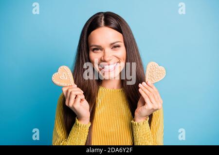 Photo portrait d'une fille souriante tenant deux biscuits de pain d'épice en forme de coeur isolé sur fond bleu pastel Banque D'Images