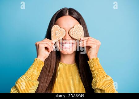 Photo portrait d'une femme couvrant deux yeux avec du pain d'épice en forme de cœur cookies isolés sur fond bleu pastel Banque D'Images