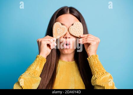 Photo portrait d'une femme choquée couvrant deux yeux en forme de cœur biscuits au pain d'épice isolés sur fond bleu pastel Banque D'Images