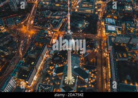 Berlin, Allemagne Alexanderplatz TV Tower après coucher de soleil à Dusk avec de belles rues éclairées dans les lumières orange d'un grand paysage urbain, vue aérienne Banque D'Images