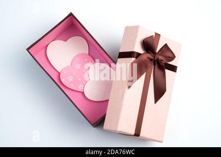 Coeurs roses et blancs dans une boîte cadeau sur fond clair. Banque D'Images