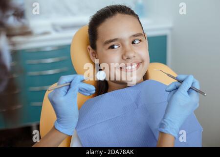 African american docteur en gants de caoutchouc avec outil de stomatologie pour traite la dent d'un petit enfant souriant Banque D'Images