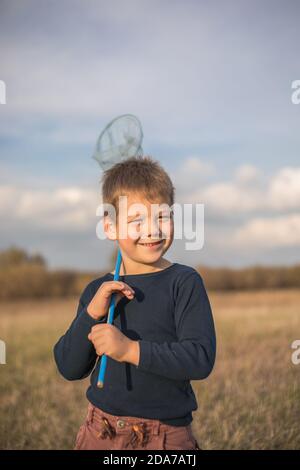 Jeune garçon avec un pré de marche à filet de papillon. Enfant jouant attrapant des insectes. Activités estivales saisonnières pour les enfants en plein air. Apprentissage faune animale monde ho Banque D'Images