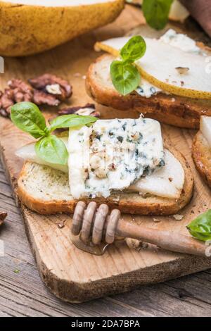 Toast ou canape au fromage de chèvre, basilic, miel, noix. Délicieux hors-d'œuvre, idéal comme apéritif. Banque D'Images