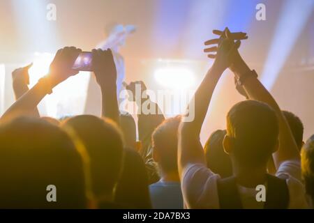 Les gens font la silhouette prendre des photos ou enregistrer des vidéos de concert avec leur smartphone. La foule fait la fête devant la scène. Photographie Banque D'Images