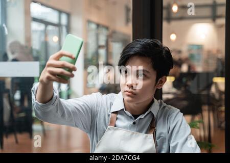 le beau selfie de barista utilise un appareil photo pour smartphone pendant les pauses Banque D'Images