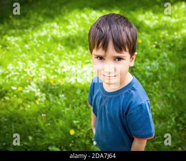 Adorable garçon debout sur fond d'herbe verte Banque D'Images