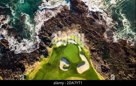 Vue sur le terrain de golf de la plage de galets à côté l'océan avec des vagues qui frappent les rochers à marée basse À Monterey, Californie Banque D'Images