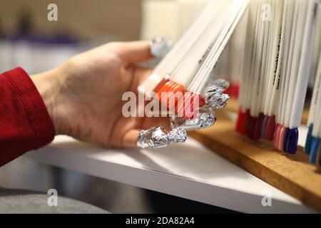 La main femelle avec du papier d'aluminium sur les ongles contient des échantillons de palette de couleur de clou. Banque D'Images