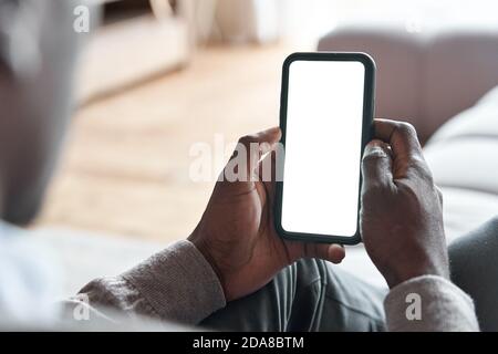 Homme africain tenant un téléphone avec écran blanc maquette pour les annonces d'applications à la maison. Banque D'Images