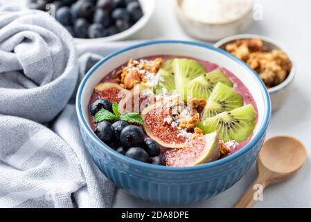 Bol de smoothie aux fruits Superfood avec kiwi, figues, granola, myrtilles et noix de coco. Vue en gros plan Banque D'Images