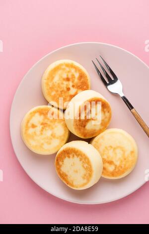 Syrniki, beignets de fromage sur une assiette sur fond rose, vue du dessus. Cuisine russe et ukrainienne crêpes au fromage doux Banque D'Images