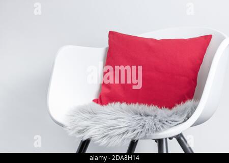 Vue latérale d'une chaise moderne en plastique blanc avec un oreiller rose et un coussin de siège en fourrure artificielle grise, utilisé comme arrière-plan de conception pour interio Banque D'Images